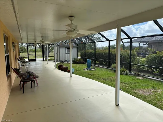 View of patio / terrace with an outbuilding, ceiling fan, a lanai, and a shed