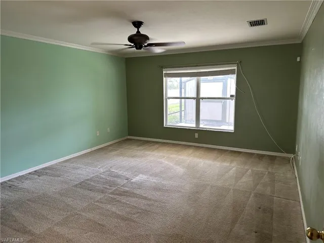 Unfurnished room with carpet flooring, crown molding, ceiling fan, and visible vents