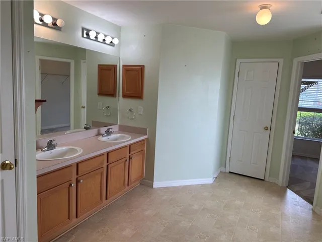 Full bathroom featuring double vanity, a sink, and baseboards