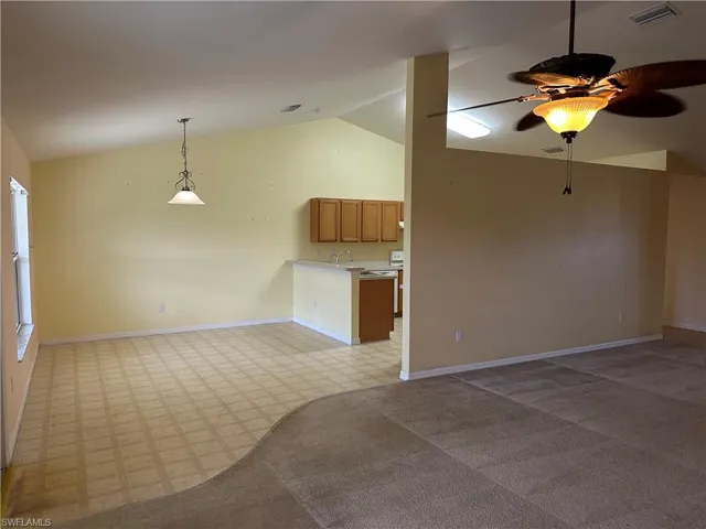 Unfurnished living room featuring baseboards, visible vents, lofted ceiling, and ceiling fan