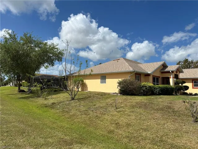 View of home's exterior featuring glass enclosure, a lawn, and stucco siding