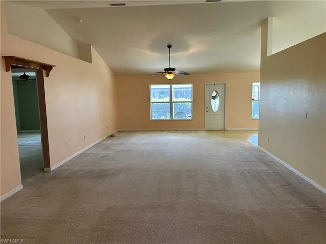 Living room with a ceiling fan, baseboards, lofted ceiling, and light colored carpet