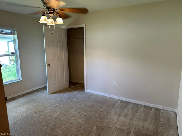 Carpeted spare room featuring baseboards and a ceiling fan
