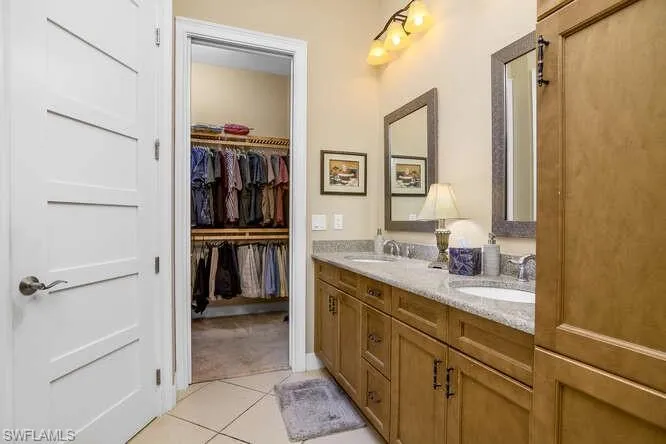 Owner's Bathroom featuring double vanity, light tile patterned floors, and a spacious walk-in-closet