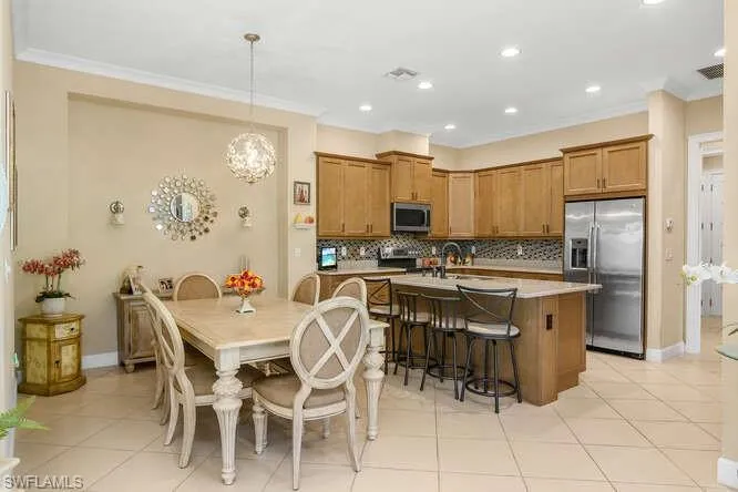 Kitchen with stainless steel appliances, an island with sink, wood finish cabinetry, crown molding, and a breakfast bar.