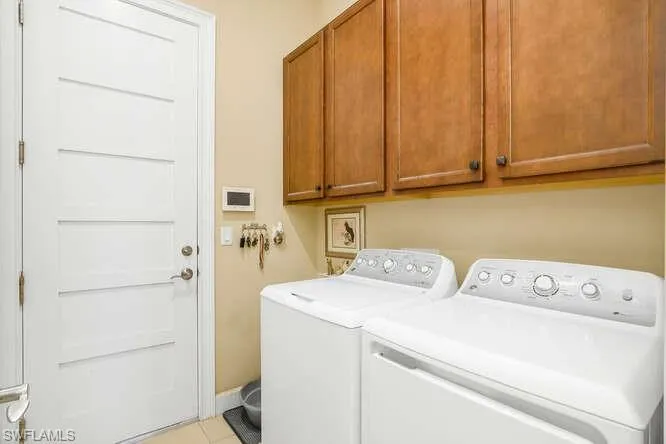 Laundry room with cabinet space, washer and clothes dryer, and light tile patterned flooring