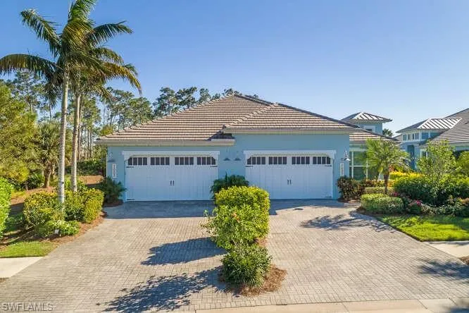 View of front facade featuring driveway, an attached garage, a tile roof, and stucco siding
