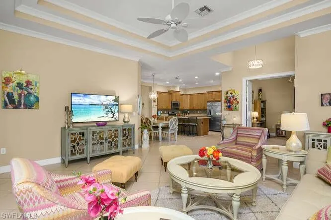 Great room featuring a tray ceiling, ceiling fan, light tile flooring, recessed lighting, and crown molding.