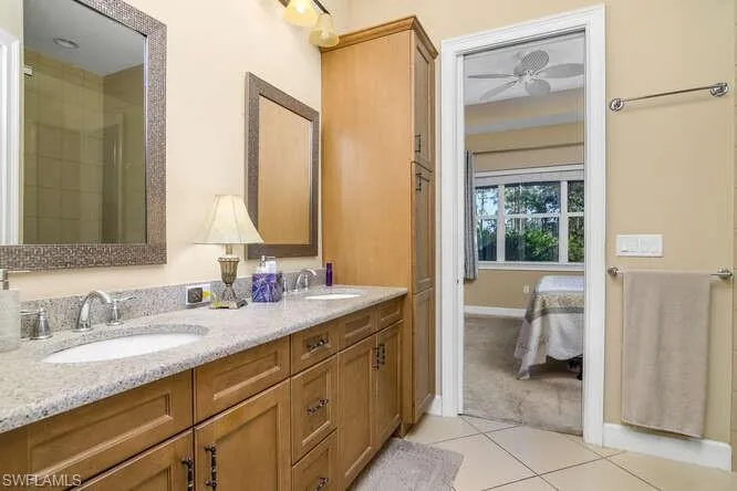 Owner's Bathroom featuring double vanity, light tile patterned floors, ensuite bathroom, and a ceiling fan