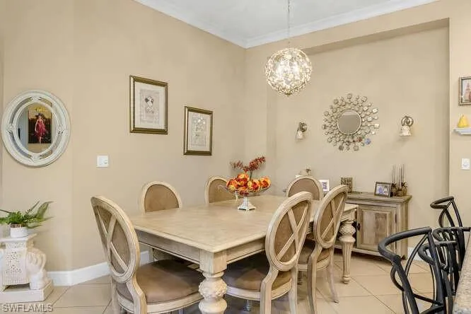 Dining space with light tile floors, a chandelier, and crown molding.