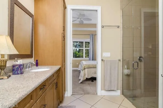 Owner's Full bath with a shower stall, dual sinks, vanity, ensuite bathroom, and light tile patterned floors