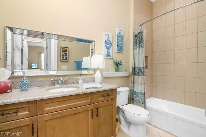 Guest Bathroom with vanity, shower / bath combination with curtain, and light tile patterned floors