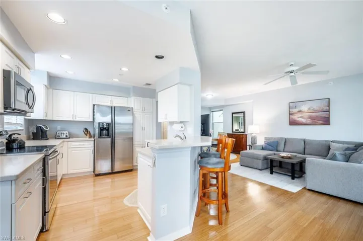 Kitchen with white cabinetry, kitchen peninsula, a breakfast bar area, stainless steel appliances, and light hardwood / wood-style flooring