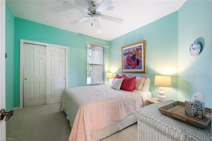 Bedroom with ceiling fan, a closet, and light colored carpet