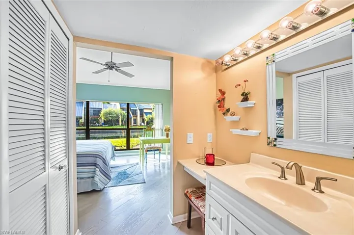 Bathroom with a closet, vanity, ensuite bath, and light wood-style flooring