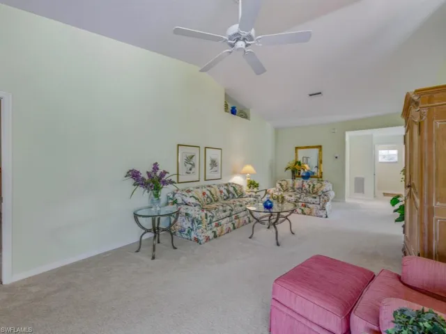 Carpeted living area featuring high vaulted ceiling and ceiling fan