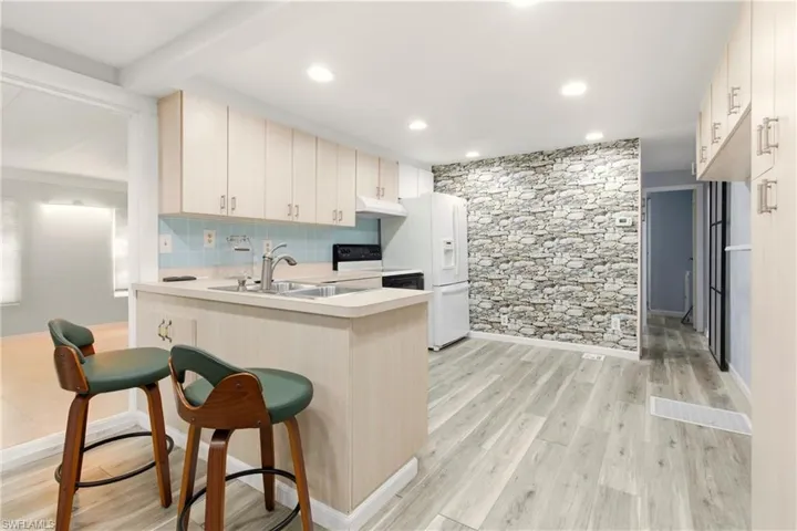 Kitchen with light countertops, light wood-type flooring, a breakfast bar, a peninsula, and electric stove