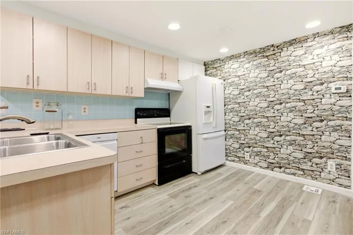 Kitchen with light wood finish cabinetry, electric range, light countertops, light wood-style flooring, and recessed lighting