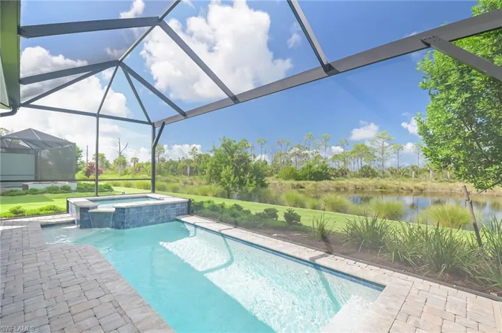 View of swimming pool featuring glass enclosure, a water view, and an in ground hot tub