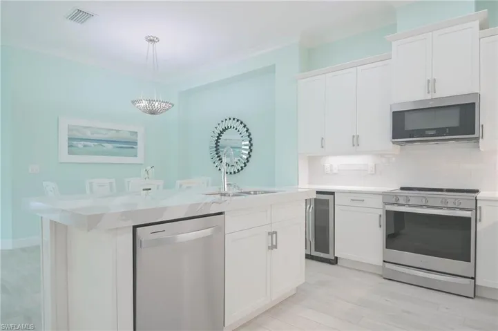 Kitchen featuring white cabinets, pendant lighting, stainless steel appliances, and light hardwood / wood-style flooring
