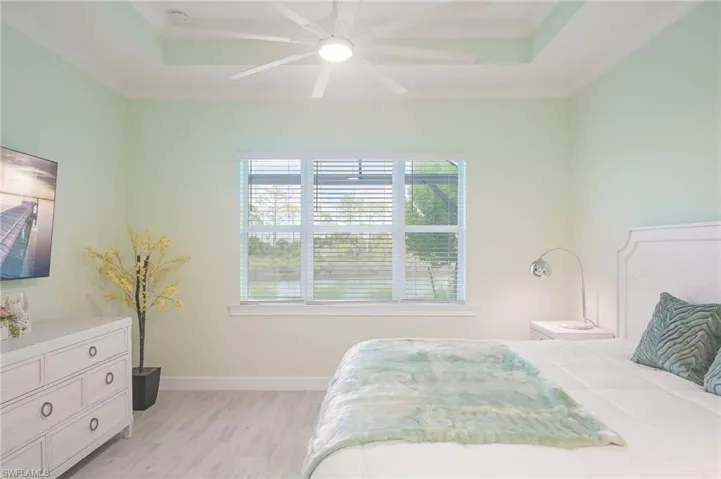 Bedroom with crown molding, ceiling fan, a raised ceiling, and light wood-type flooring