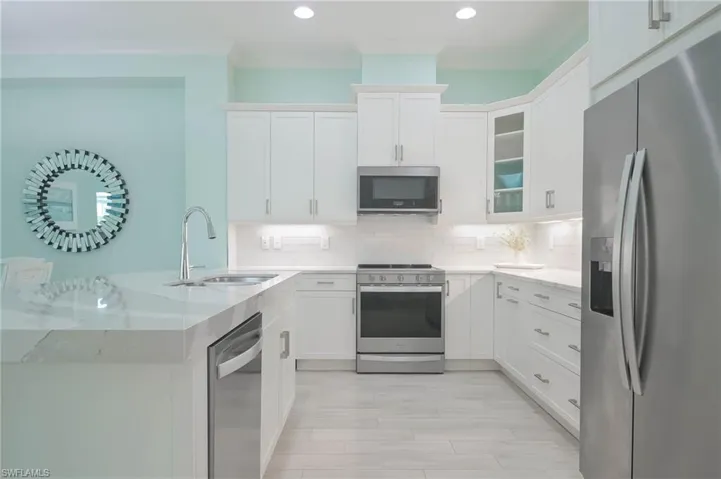 Kitchen featuring backsplash, appliances with stainless steel finishes, light hardwood / wood-style floors, sink, and white cabinetry