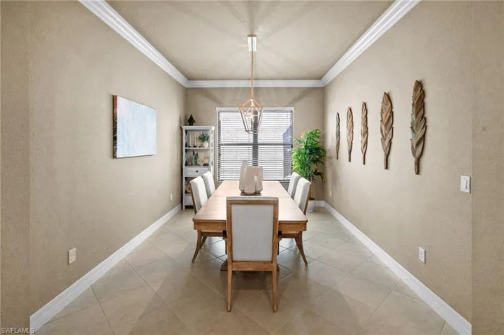 Dining space featuring a textured wall, crown molding, and light tile patterned floors