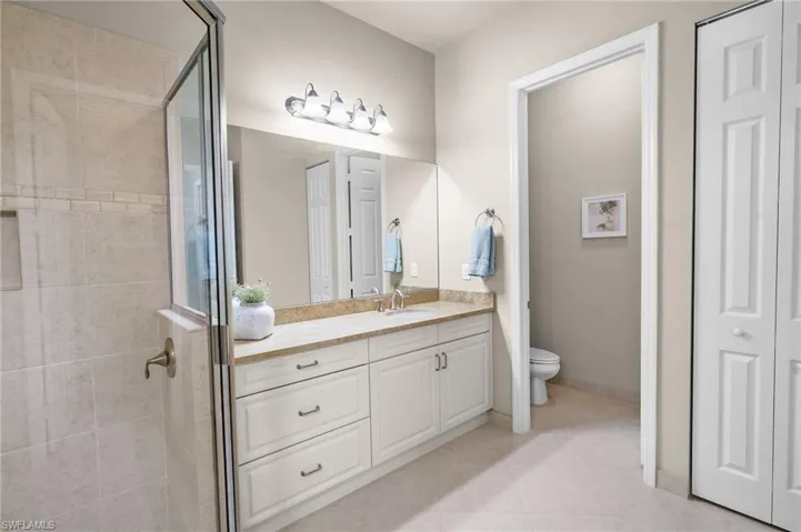 Bathroom featuring a stall shower, vanity, a closet, and light tile patterned flooring