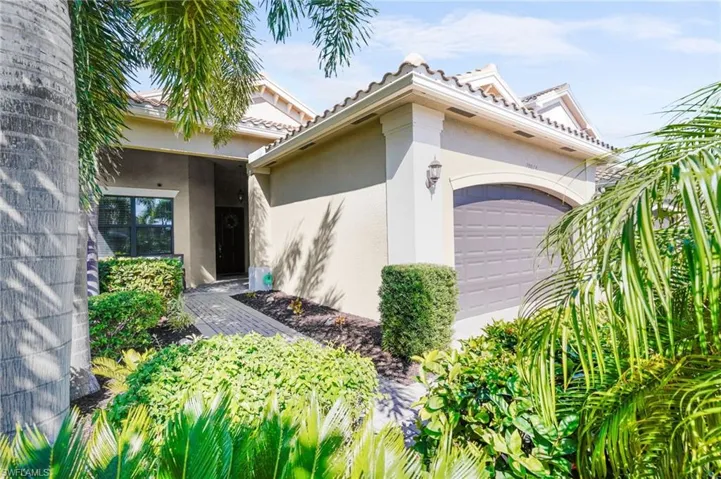 View of exterior entry with a garage, stucco siding, and a tiled roof