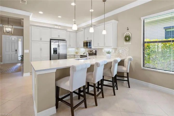 Kitchen featuring appliances with stainless steel finishes, a breakfast bar, decorative backsplash, a peninsula, and decorative light fixtures