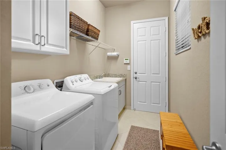 Laundry area with cabinet space, light tile patterned flooring, and independent washer and dryer
