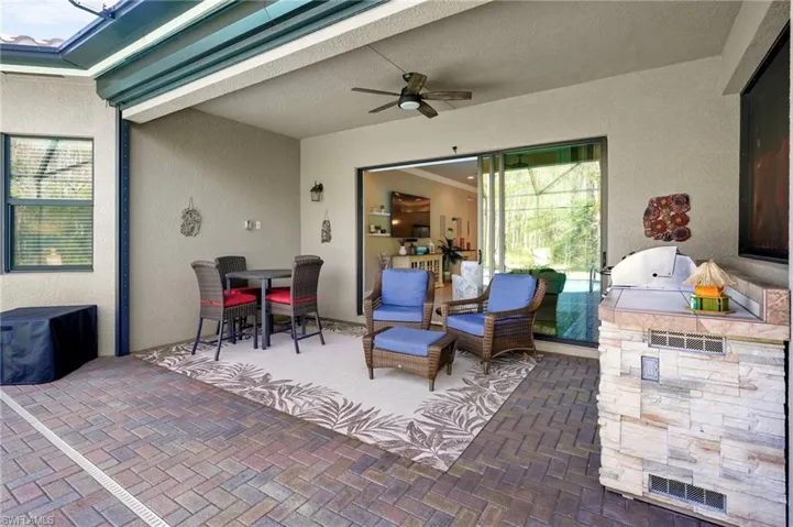 View of patio featuring exterior kitchen, outdoor dining area, and a ceiling fan