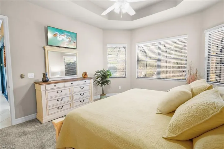 Bedroom with a tray ceiling, ceiling fan, and light colored carpet
