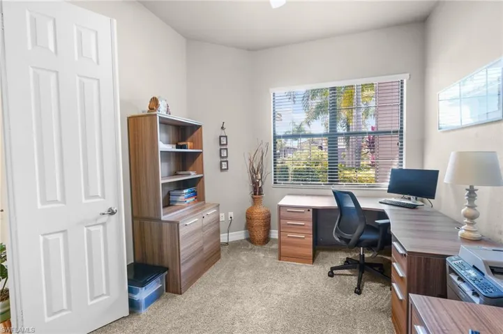 Office area featuring light carpet and baseboards