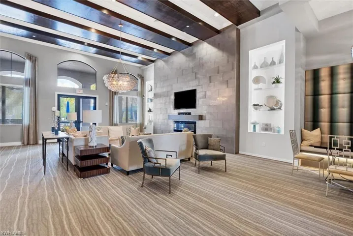 Living room with beam ceiling, built in shelves, and a glass covered fireplace