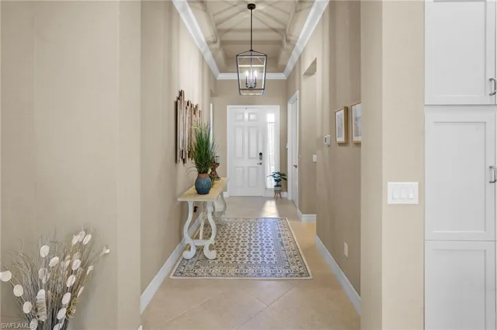 Foyer with light tile patterned floors, a high ceiling, a chandelier, and ornamental molding