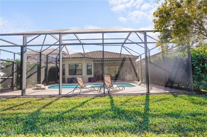 Swimming pool featuring glass enclosure, a yard, a patio area, and a sunroom