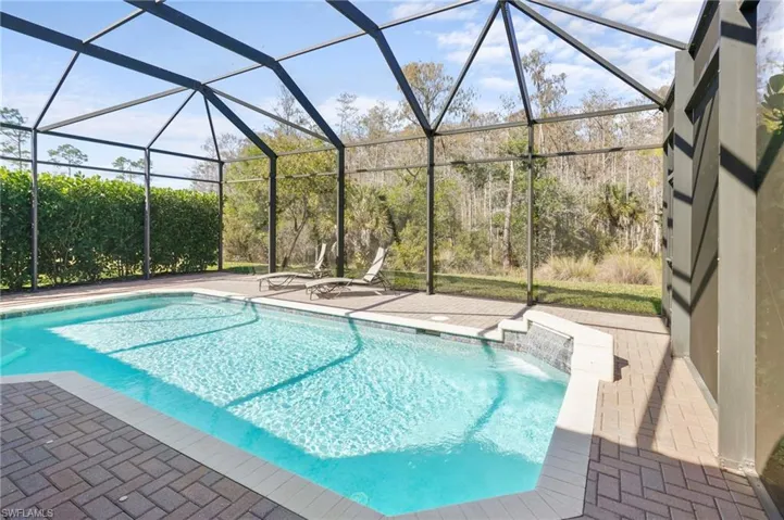 Swimming pool with glass enclosure, a sunroom, and a patio area