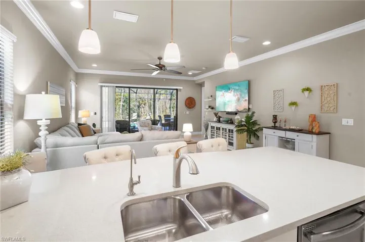 Kitchen featuring hanging light fixtures, light stone countertops, a ceiling fan, open floor plan, and recessed lighting
