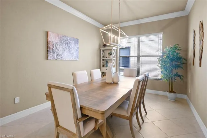 Dining space featuring ornamental molding, light tile patterned flooring, and a chandelier