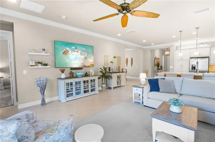 Living area with ornamental molding, a ceiling fan, and recessed lighting