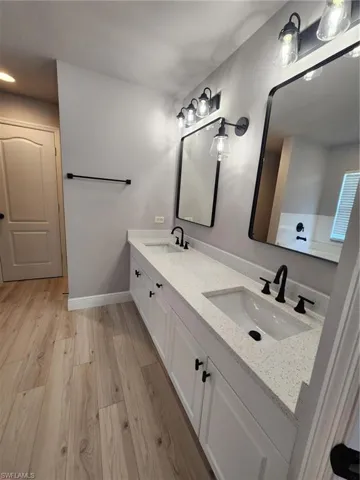 Bathroom featuring double sink vanity and wood-type flooring