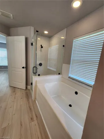 Bathroom featuring plus walk in shower and hardwood / wood-style flooring