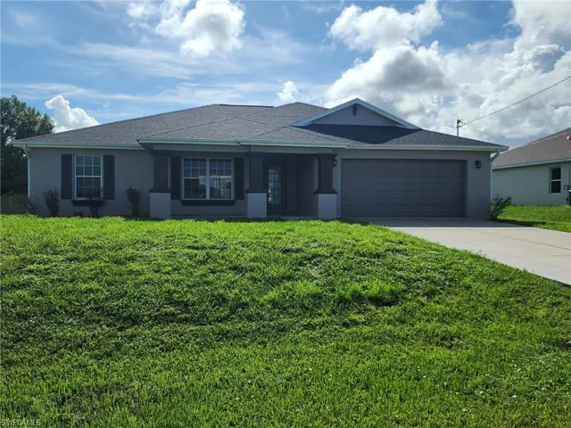 Ranch-style home featuring a front lawn and a garage