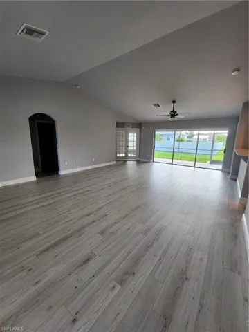 Unfurnished living room featuring ceiling fan, vaulted ceiling, and light hardwood / wood-style floors