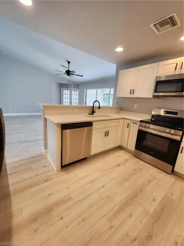 Kitchen featuring ceiling fan, dishwashing machine, range, light wood-type flooring, and sink