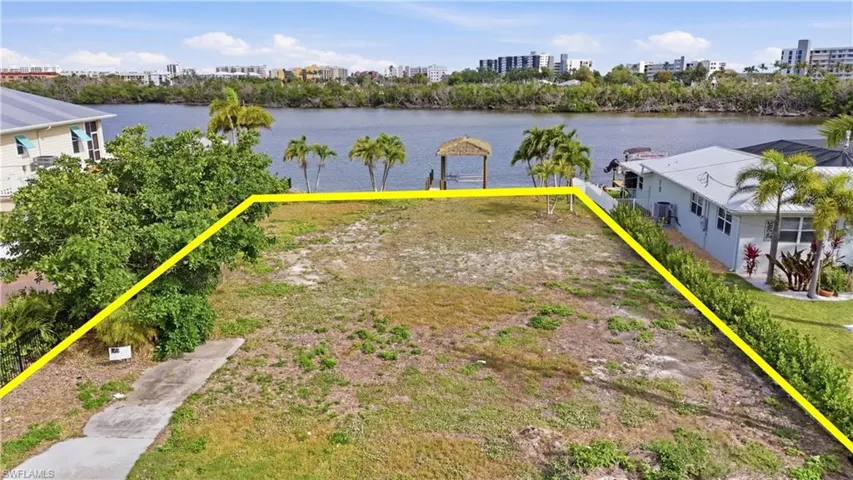 View of urban area with property boundaries highlighted and a nearby body of water - Virtually Edited Image