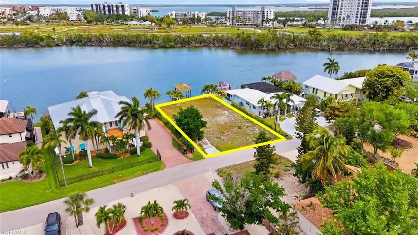 View of urban area with property parcel outlined and a nearby body of water - Virtually Edited Image