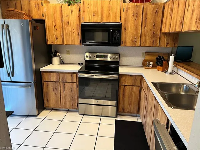 Kitchen featuring wood-finish cabinetry, white countertops, stainless steel appliances, and white square tile flooring