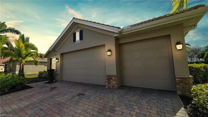 Back house at dusk featuring a patio, a lanai, and a lawn
